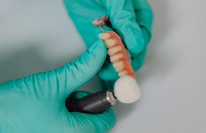 Dental technician in clinic laboratory polishing a custom acrylic denture restoration.